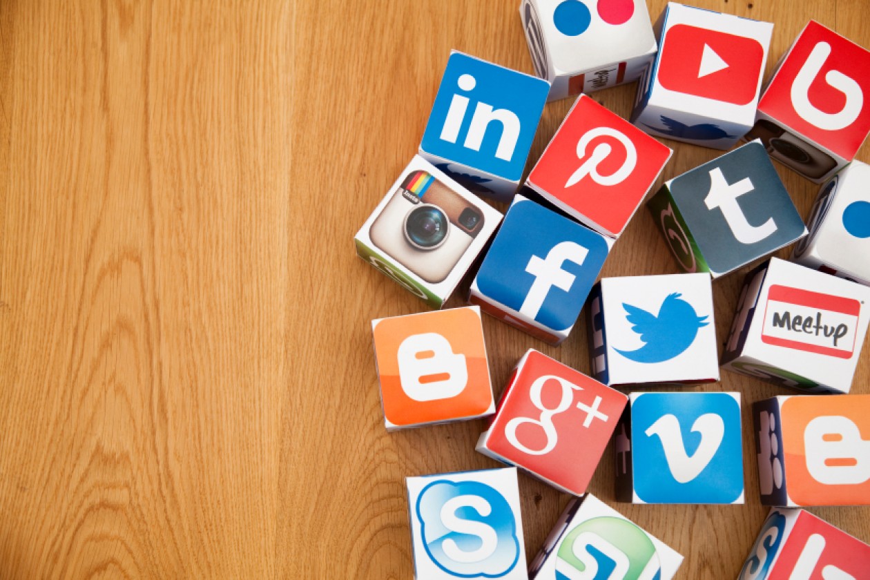 Social media logos pasted onto cradboard cubes lay casually on a wooden table.