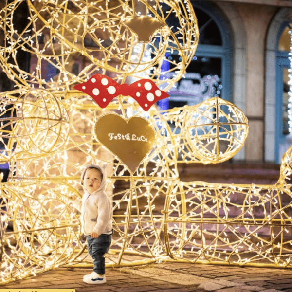 Kid standing next to a Christmas decoration