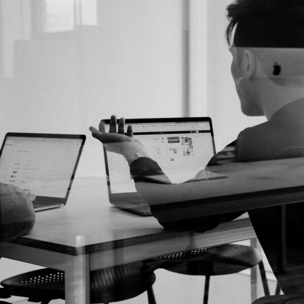 Two people sitting and talking in front of their computers