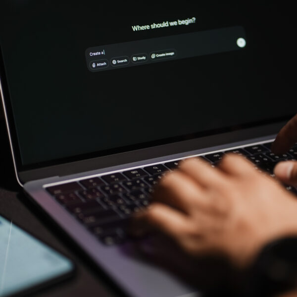 The hands of a man using a laptop or smartphone to operate artificial intelligence (AI), inputting commands and interacting with AI assistants.