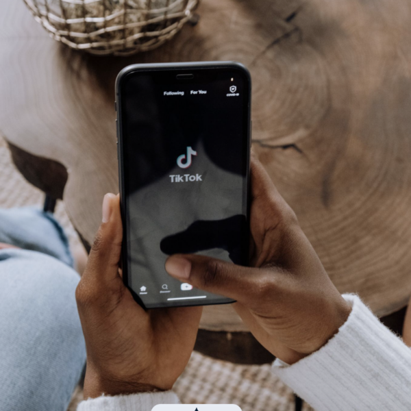 A woman holding a phone looking on TikTok